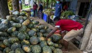 A vendor sorts pumpkins as customers buy vegetables in Hambantota on December 22, 2021. (Photo by ISHARA S. KODIKARA / AFP)
