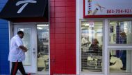 Co-owner Chris Toliver (L) arrives as his father Herbert Toliver (C) trims hair and talks with customers at Toliver's Mane Event Barber Shop in Charleston, South Carolina, on February 2, 2024. (Photo by Jim WATSON / AFP)
