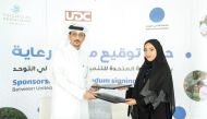 UDC Executive Director of Public Services Abdullatif Ali Al-Yafei and Founder of the Autism Parents Platform Hamda Al-Hitmi exchanging documents after signing the agreement.