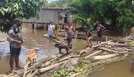 This photo released by the Papua New Guinea Police and received by AFP on March 25, 2024 shows locals on a makeshift bridge in the flooded Angriman Village in Angoram District, East Sepik, Papua New Guinea. (Photo by Handout / PNG Police / AFP) 