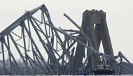 The steel frame of the Francis Scott Key Bridge lies in the water after it collapsed in Baltimore, Maryland, on March 26, 2024. Photo by Mandel NGAN / AFP.