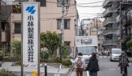 A woman points her finger at the signage of Kobayashi Pharmaceutical as she walks past the company's office in Tokyo on March 28, 2024. Photo by Yuichi YAMAZAKI / AFP