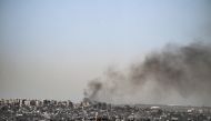 This picture taken from Israel's southern border with the Gaza Strip shows smoke billowing behind destroyed buildings due to Israeli strikes on the besieged Palestinian territory on April 2, 2024. (Photo by RONALDO SCHEMIDT / AFP)
