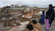 Onlookers gaze towards municipal workers using heavy machinery to level the ground after damage due to floodwaters following heavy rains on the outskirts of Quetta on April 15, 2024. (Photo by Banaras Khan / AFP)