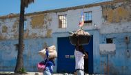 People walk with their hands over their faces to protect themselves from the stench of decomposing bodies as they pass the National Penitentiary in Port-au-Prince, Haiti, March 4, 2024. (Photo by Clarens Siffroy / AFP)