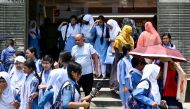 Students leaving their school compound carry umbrellas on a hot summer day in Dhaka on April 28, 2024. (Photo by Munir UZ ZAMAN / AFP)
 