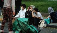 People from a Pro-Palestinian encampment sit on the sidewalk along I St NW after Law Enforcement cleared George Washington University's University Yard at on May 8, 2024 in Washington, DC. (Photo by Kent Nishimura / GETTY IMAGES NORTH AMERICA / Getty Images via AFP)
