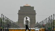 A man wears a scarf as he walks past the India Gate on a hot summer day in New Delhi on June 18, 2024. Photo by Arun SANKAR / AFP.