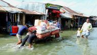 People push a handcart carrying supplies through the flood at Fenchuganj in Sylhet on July 3, 2024. (Photo by Mamun Hossain / AFP)
