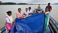 Members of a medical team hold a tarpaulin as a woman delivers a child on a boat on July 3, 2024. (Photo by Biju Boro / AFP)
 