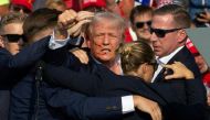 Republican candidate Donald Trump is seen with blood on his face surrounded by secret service agents as he is taken off the stage. (Photo by Rebecca Droke / AFP)
 