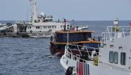 This file photo taken on August 22, 2023 shows Chinese coast guard ships (L and R) corralling a Philippine civilian boat chartered by the Philippine navy to deliver supplies to the Philippine navy ship BRP Sierra Madre, in disputed waters of the South China Sea. Photo by Ted ALJIBE / AFP