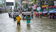 People carrying umbrellas, wade through a flooded street amid rainfall in Feni on August 22, 2024. (Photo by AFP)
