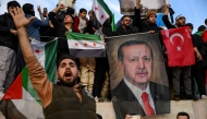 People hold a banner featuring Turkish President Recep Tayyip Erdogan as members of the Syrian community and supporters gather to celebrate the fall of Syrian president Bashar al-Assad in the face of an offensive by Islamist-led rebels, in Istanbul on December 8, 2024. Photo by Yasin AKGUL / AFP.