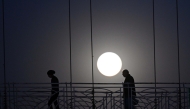People walk on a bridge as a full moon is seen over Islamabad, Pakistan, on Feb. 12, 2025. (Xinhua/Ahmad Kamal)
