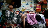 In this photo taken on February 23, 2025 alleged scam centre workers and victims rest during a crackdown operation by the Karen Border Guard Force (BGF) on illicit activity, at the border checkpoint with Thailand in Myanmar's eastern Myawaddy township. (Photo by AFP)

