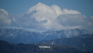 Snow dusted mountains stand on the skyline behind a view of the Hollywood sign following rain storms, as seen from the Kenneth Hahn State Recreation Area, in Los Angeles, California on March 7, 2025. (Photo by Patrick T. Fallon / AFP)
