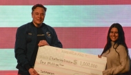 Elon Musk gives a $1 million check made to the order of Ekaterina Diesler during a town hall in Green Bay, Wisconsin on March 30, 2025. (Photo by Robin LEGRAND / AFP)
