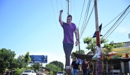 People walk past a giant cardboard image of Ecuador's President Daniel Noboa in Olon, Santa Elena province, Ecuador, on April 14, 2025, the day after the presidential runoff election.  (Photo by Raul Arboleda / AFP)