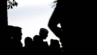 File photo: Silhouettes of migrants. (Photo by Jens Schlueter / AFP)