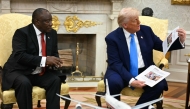 US President Donald Trump shows pictures and articles as he meets with South African President Cyril Ramaphosa in the Oval Office of the White House in Washington, DC, on May 21, 2025. 