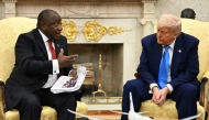 US President Donald Trump hands papers to South African President Cyril Ramaphosa during a meeting in the Oval Office of the White House in Washington, DC, on May 21, 2025. (Photo by Jim WATSON / AFP)
