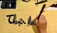 This photo taken on May 15, 2025 shows Hoang Thi Thanh Huyen learning calligraphy at the home of calligrapher Nguyen Thanh Tung in Hanoi. (Photo by Nhac Nguyen / AFP) / 