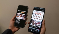 This photo illustration taken in Hong Kong on June 20, 2025 shows a person holding two mobile phones with two viral AI-generated videos of students and an old woman voicing their opinions on the impeachment of Philippine Vice President Sara Duterte. (Photo by Yan Zhao / AFP) 