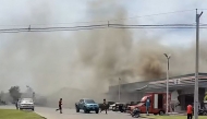 This frame grab from UGC video footage taken and posted on Facebook by Chatchak Ratsamikaeo on July 24, 2025 shows smoke billowing from the roof of a convenience store attached to a petrol station in Sisaket province after it was hit by a rocket strike from Cambodia. Photo by Courtesy of Facebook user Chatchak Ratsamikaeo / AFP