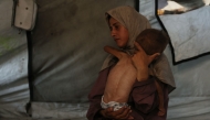 Hidaya, a 31-year-old Palestinian mother, carries her 18-month-old sick son Mohammed al-Mutawaq, who is also displaying signs of malnutrition, inside their tent at the Al-Shati refugee camp, west of Gaza City, on July 24, 2025. Photo by Omar AL-QATTAA / AFP.