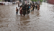 Commuters wade through a flooded street after heavy rainfall in Lahore on July 23, 2025. (Photo by Arif ALI / AFP)

