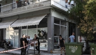 People stand next to a damaged shop following a strong blast in Thessaloniki on July 26, 2025. (Photo by Sakis Mitrolidis / AFP)
