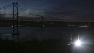 This photograph shows the 25th April bridge over the Tagus river with the lights off following a massive power cut affecting the entire Iberian peninsula and the south of France, in Lisbon on April 28, 2025. Photo by Patricia DE MELO MOREIRA / AFP.
