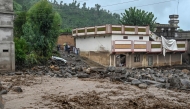 Villagers (center, L) stand near a building as floodwater levels rise in the Buner district of Pakistan's Khyber Pakhtunkhwa province on August 18, 2025. Photo by Abdul MAJEED / AFP