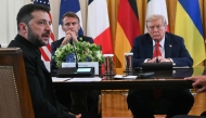 (L/R) Ukrainian President Volodymyr Zelensky speaks as French President Emmanuel Macron and US President Donald Trump listen during a meeting with European leaders in the East Room of the White House in Washington, DC, on August 18, 2025. (Photo by Andrew Caballero-Reynolds/ AFP)
