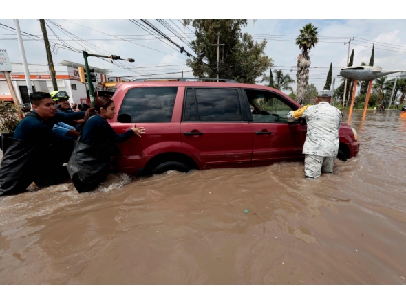 Firefighters and a member of the National Guard assist a driver stranded in floodwater after heavy rains caused the Arroyo Seco River to overflow in Tlajomulco de Zٌْiga, Jalisco, Mexico, on September 9, 2025. (Photo by ULISES RUIZ / AFP)

