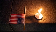 A US flag and a candle sit on a step during a candlelight vigil and prayer event for Turning Point USA Founder Charlie Kirk on September 10, 2025 in Seattle, Washington. David Ryder/Getty Images/AFP 