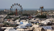 An idle ferris wheel stands near tents at a camp for displaced people in Khan Yunis in the southern Gaza Strip, on September 29, 2025. (Photo by Omar Al-Qattaa / AFP)