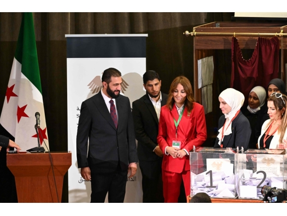 Syria's interim President Ahmed al-Sharaa (left) visits the poling station where members of Syrian local committees have been casting their votes in the country's selection process to designate an interim parliament, in Damascus on October 5, 2025. (Photo by Louai Beshara / AFP)
