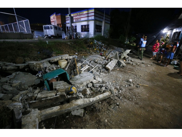 Police stand next to the rubble of a collapsed wall in Mati town, Davao Oriental province, in southern island of Mindanao, after a 7.4-magnitude earthquake struck the province. (Photo by Mark NAVALES / AFP)
