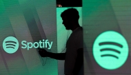 File: A man checks his smartphone whilst standing amongst illuminated screens bearing the Spotify Technology SA logo in this arranged photograph in London, UK, on Tuesday, June 26, 2018. (Photo by Chris Ratcliffe/Bloomberg)
