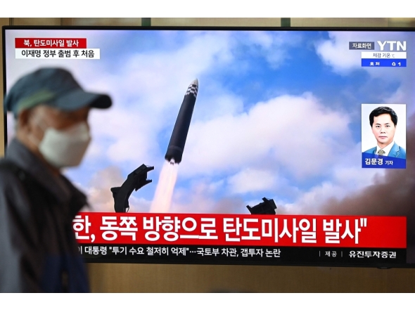 A man walks past a television screen showing a news broadcast with file footage of a North Korean missile test, at a train station in Seoul on October 22, 2025. (Photo by Jung Yeon-je / AFP)