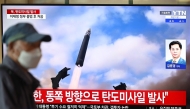 A man walks past a television screen showing a news broadcast with file footage of a North Korean missile test, at a train station in Seoul on October 22, 2025. (Photo by Jung Yeon-je / AFP)