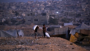 Palestinian children carry salvaged items in Khan Yunis, in the southern Gaza Strip on October 25, 2025. Photo by Bashar TALEB / AFP
