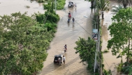 People wade through the water along a submerged street in Tuguegarao City, Cagayan province, north of Manila on November 11, 2025, as flood waters continue to inundate homes due to heavy rains brought about by Super Typhoon Fung-wong. Photo by John Dimain / AFP