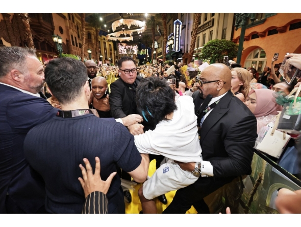 This picture by The Straits Times taken November 13, 2025 and provided on November 14 shows a man (C) accused of attacking pop star Ariana Grande being grabbed by security guards as co-star Cynthia Erivo (3rd L) reacts at the premiere of their film 
