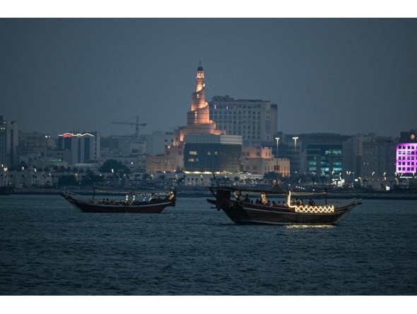 Tourists ride traditional boats along the corniche promenade in Doha on November 12, 2025. Photo by Mahmud HAMS / AFP