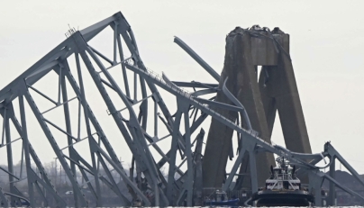 The steel frame of the Francis Scott Key Bridge lies in the water after it collapsed in Baltimore, Maryland, on March 26, 2024. Photo by Mandel NGAN / AFP.

