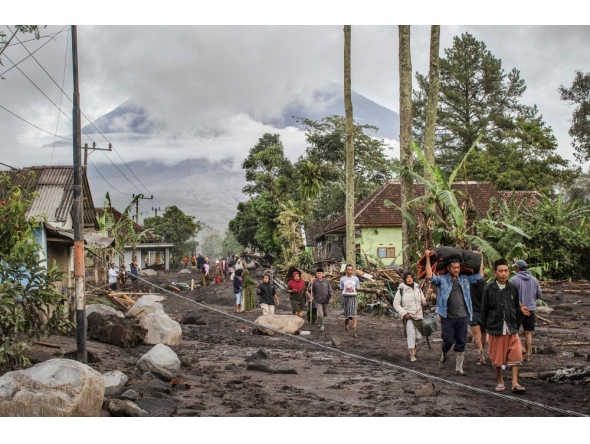 People walk on ground covered in volcanic ash after a pyroclastic flow during yesterday痴 eruption of Mount Semeru in Supiturang village, Lumajang, East Java on November 20, 2025. (Photo by Agus Harianto / AFP)
 