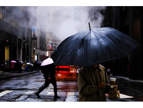 People walk on the street as the rain pours in the Manhattan borough of New York City on November 19, 2025. (Photo by CHARLY TRIBALLEAU / AFP)
